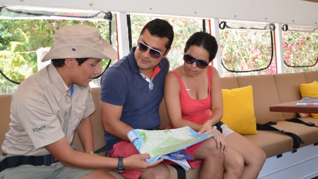 Un guía mostrando un mapa a dos Visitantes mientras se sientan dentro de un autobús