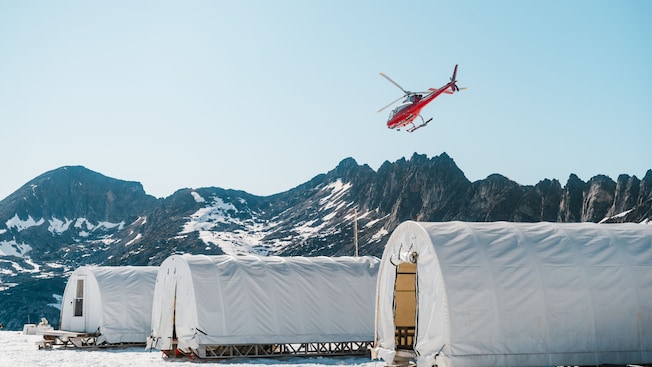 A helicopter flying over a sled dog camp on Denver Glacier, Alaska A helicopter flying over a sled dog camp on Denver Glacier, Alaska