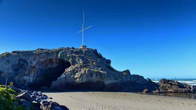 Cave Rock, a volcanic formation with a crevice at its base and a tall antenna on top, in Christchurch