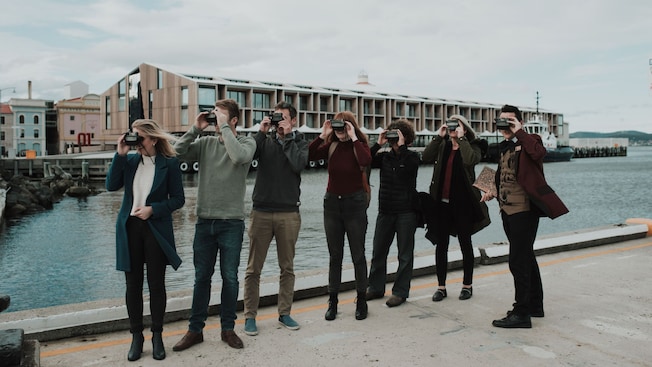 Um grupo de hóspedes e um guia turístico usando visores em um porto Um grupo de hóspedes e um guia turístico usando visores em um porto