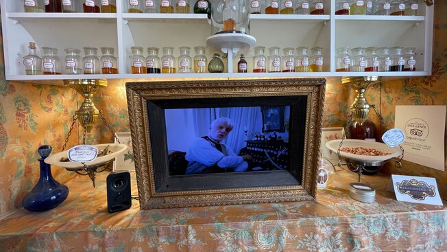 A table and shelves displaying perfume ingredients and a photo of a perfumer at Victorian Perfumery