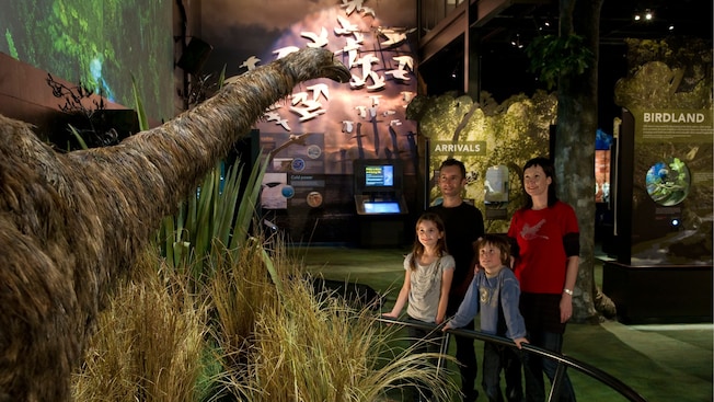 Una familia de cuatro personas admira un moa en exhibición en Zealandia Una familia de cuatro personas admira un moa en exhibición en Zealandia