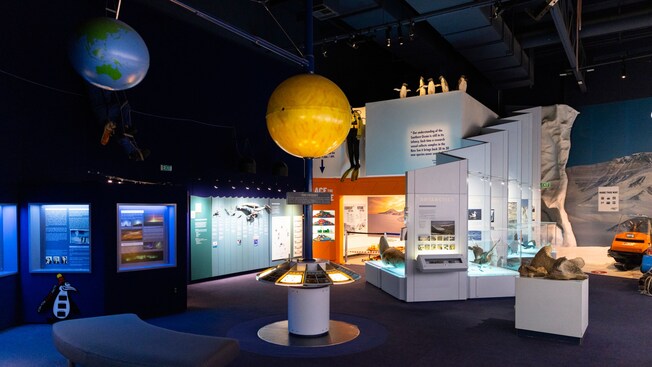 An exhibit at the International Antarctic Centre featuring hanging models of Earth and the sun along with displays showcasing Antarctica