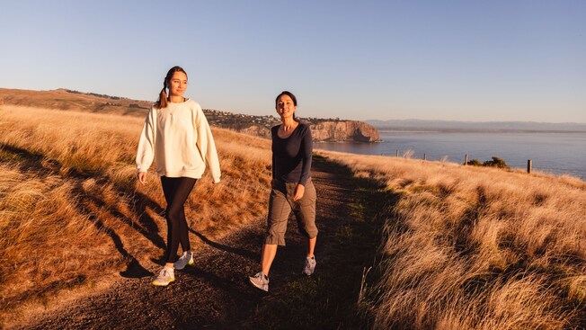 Two women walking on a pathway at Godley Head in Canterbury, New Zealand