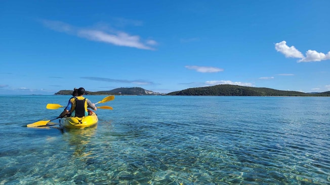 Dos personas paseando en kayak en aguas tranquilas con la costa a la distancia Dos personas paseando en kayak en aguas tranquilas con la costa a la distancia