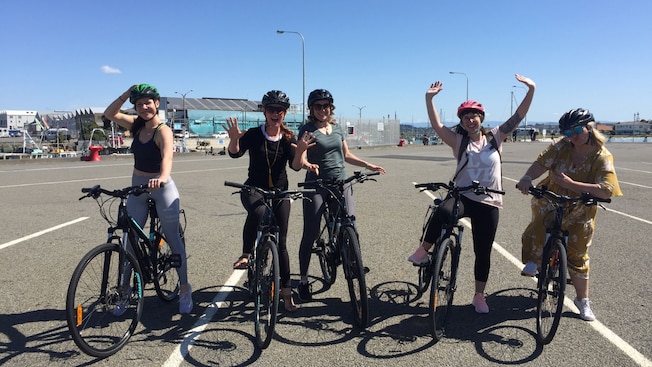 Five Guests straddling E bikes in a parking lot Five Guests straddling E bikes in a parking lot
