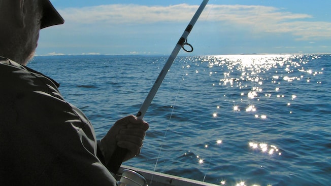 A man holding a fishing pole near the ocean A man holding a fishing pole near the ocean