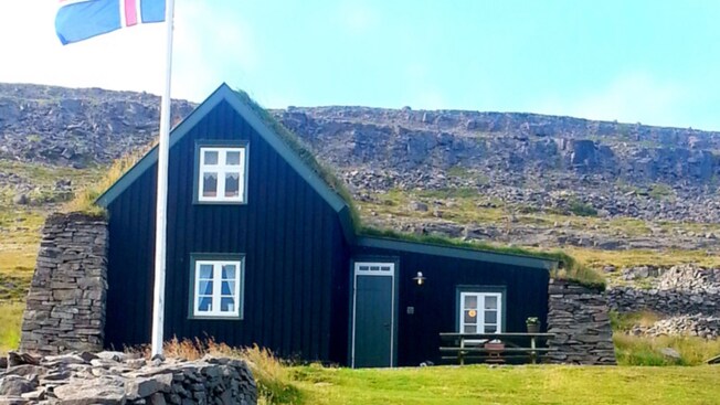 A building in the middle of the Westfjords with the flag of Iceland flying out front