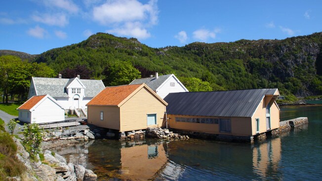Small waterfront houses surrounded by a forested landscape in Maloy, Norway