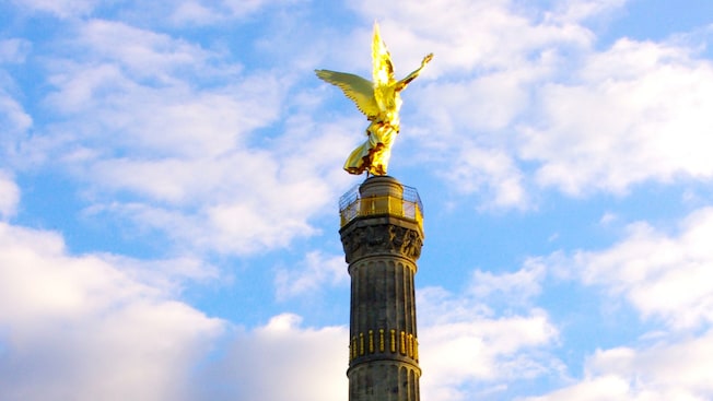 The statue of an angel holding a scepter and a laurel wreath stands atop a massive tower The statue of an angel holding a scepter and a laurel wreath stands atop a massive tower
