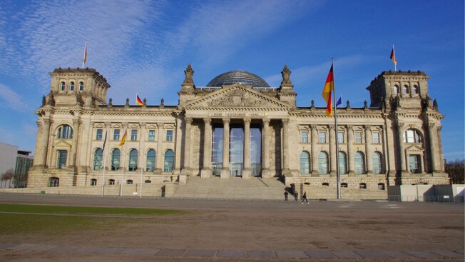 The Reichstag, a stately stone building with a columned entrance and German flags