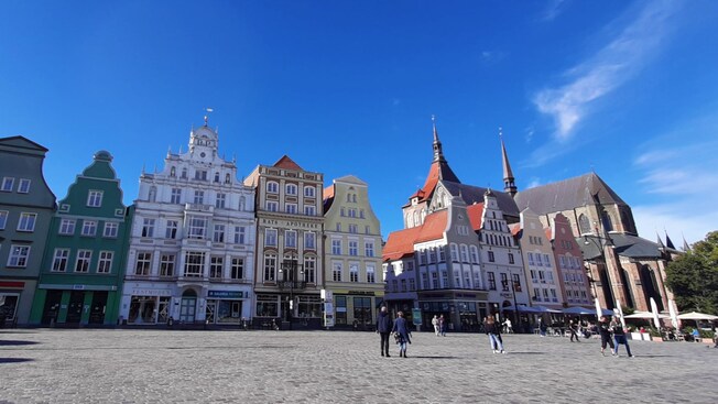 Colorful buildings lining a cobblestone public square with pedestrians