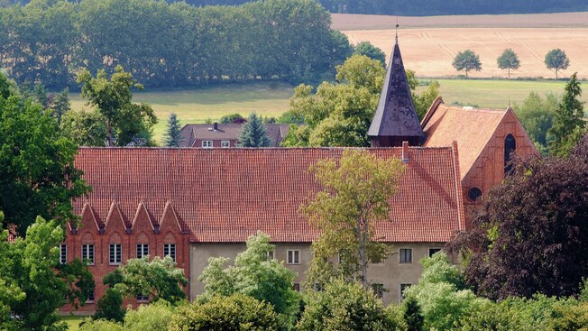 A medieval brick monastery surrounded by lush countryside