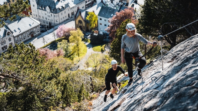 2 people climbing a steep wall with the aid of cables 2 people climbing a steep wall with the aid of cables
