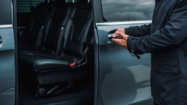 A private driver opening the door of a luxury van