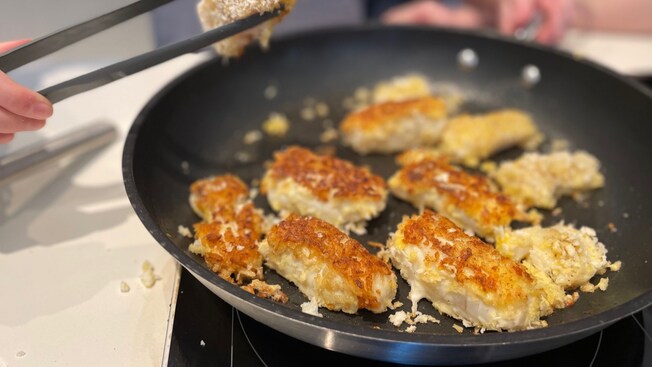 A frying pan containing pieces of fried fish