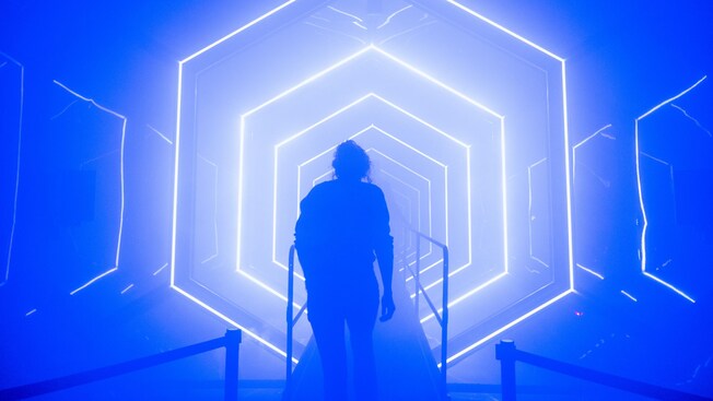 A person walks through an indoor maze on an illuminated path with stairs
