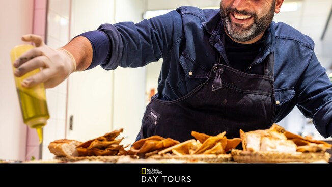 Un chef rocía aceite sobre los alimentos mientras usa un delantal y guantes en una cocina en Ámsterdam, Países Bajos
