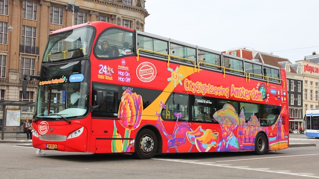 A double decker tour bus with the words ‘City Sightseeing Amsterdam’ A double decker tour bus with the words ‘City Sightseeing Amsterdam’