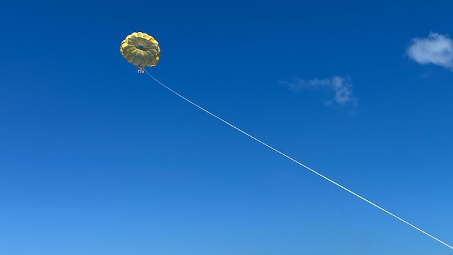 Three people parasailing near the Disney Wish cruise ship Three people parasailing near the Disney Wish cruise ship