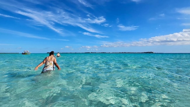 A man and a woman walking through shallow ocean water A man and a woman walking through shallow ocean water