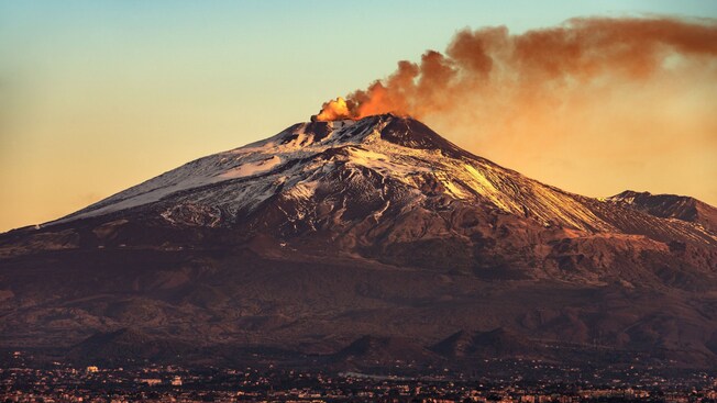 Mount Etna with smoke pouring out of the top of the volcano