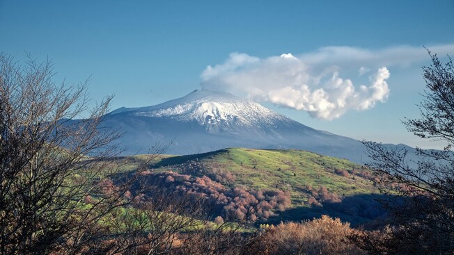 Mount Etna with smoke pouring out of the top of the volcano