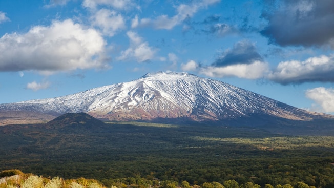 A snow covered volcano overlooks a countryside A snow covered volcano overlooks a countryside