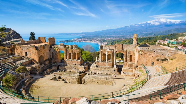 Ruins of an amphitheater, a snowy volcano and the sea