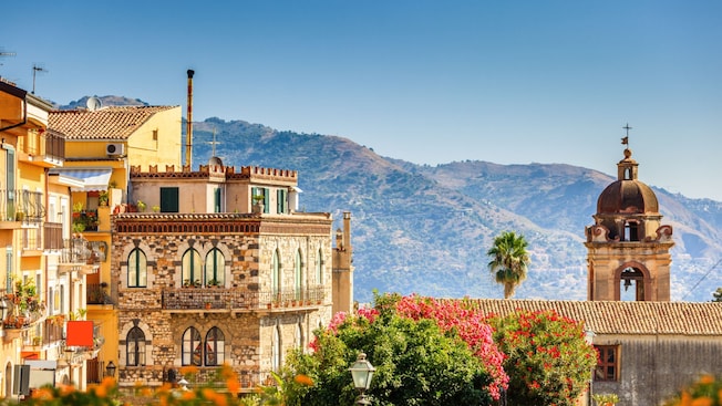 Buildings and trees against a mountain backdrop in the town of Taormina Buildings and trees against a mountain backdrop in the town of Taormina