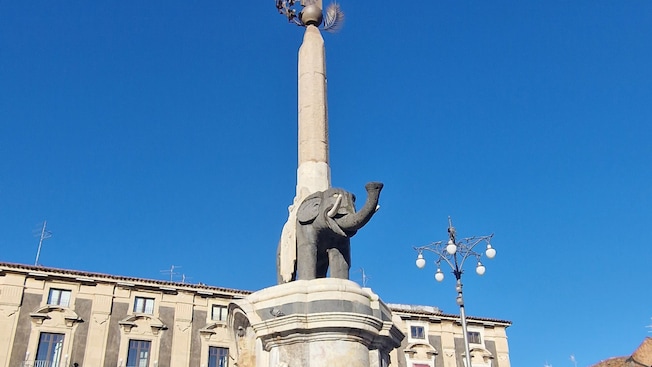 Un monumento en una plaza de la ciudad con una fuente y un elefante Un monumento en una plaza de la ciudad con una fuente y un elefante