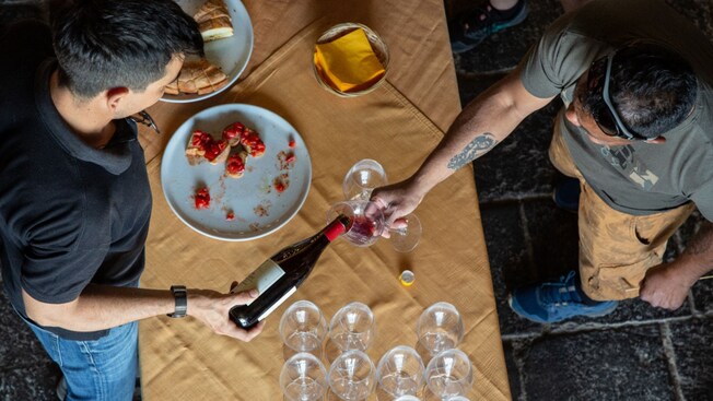 A server pours wine into the glass of a Guest