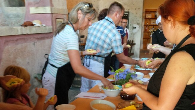 People in aprons preparing food around a long wooden table