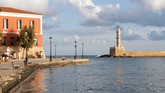 A harbor with a walking path, Venetian architecture and a nearby lighthouse