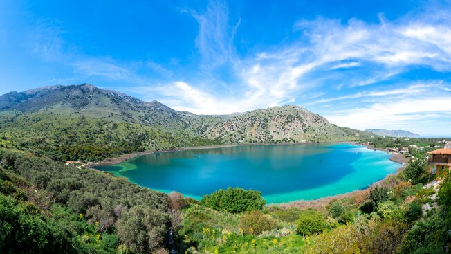 A lake surrounded by hills and next to a forest