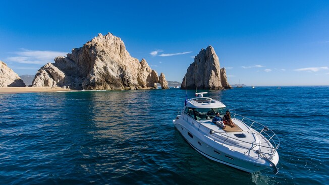 2 people relaxing on a yacht at the Arch of Cabo San Lucas rock formation