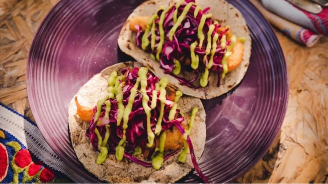 2 fish tacos topped with shredded cabbage and avocado sauce 2 fish tacos topped with shredded cabbage and avocado sauce