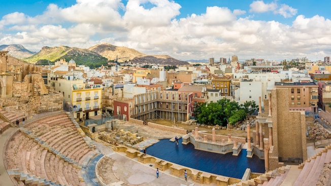 An open air theater surrounded by buildings and mountains An open air theater surrounded by buildings and mountains
