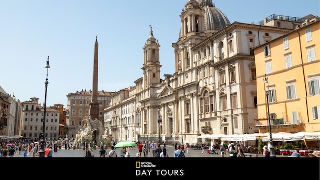 The Fountain of Four Rivers in front of the Church of Sant Agnese in Agone at the Piazza Navona, with text below that says 'National Geographic Day Tours' The Fountain of Four Rivers in front of the Church of Sant Agnese in Agone at the Piazza Navona, with text below that says 'National Geographic Day Tours'