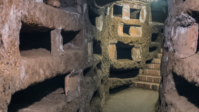 Um túnel com escadas e um muro de pedra nas catacumbas de Roma Um túnel com escadas e um muro de pedra nas catacumbas de Roma
