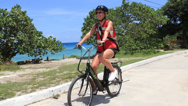 A woman riding an electric bicycle next to a beach in Cozumel, Mexico A woman riding an electric bicycle next to a beach in Cozumel, Mexico