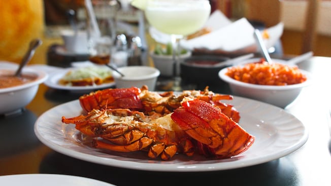 A table set with a plate of lobster, side dishes and a cocktail A table set with a plate of lobster, side dishes and a cocktail