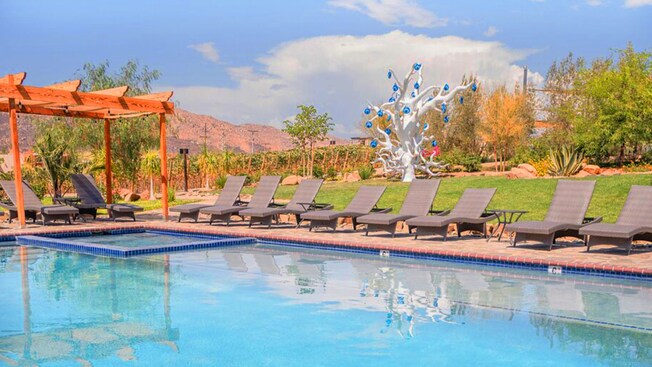 A pool and a hot tub with lounge chairs along the side