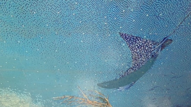 Un mosaico en el piso que muestra a una mantarraya nadando junto a algunos arrecifes de coral Un mosaico en el piso que muestra a una mantarraya nadando junto a algunos arrecifes de coral