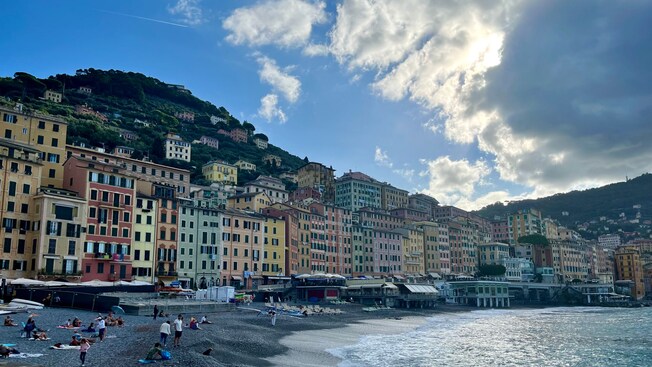 People relaxing on Spiaggia di Camogli near picturesque buildings along the shore