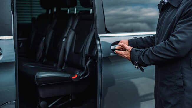 A private driver opening the door of a luxury mini van