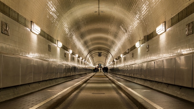 People walking along the sides of a steel and tile tunnel People walking along the sides of a steel and tile tunnel