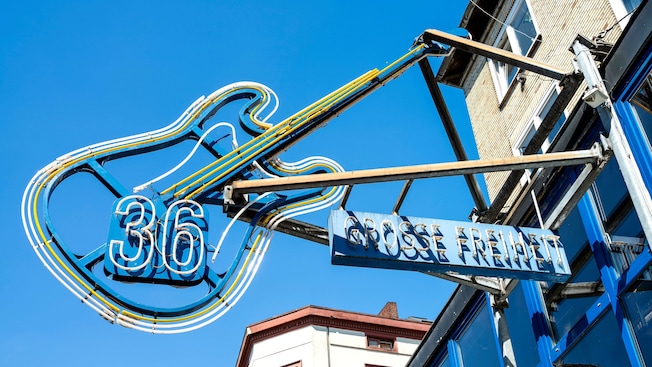 A neon sign shaped like a guitar with the number 36 at its center A neon sign shaped like a guitar with the number 36 at its center