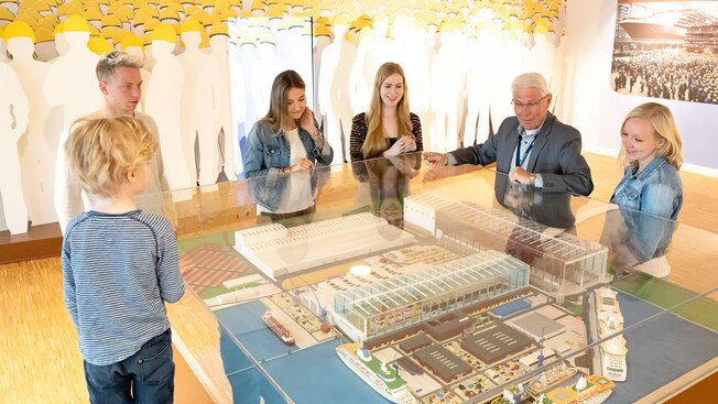 Los visitantes se paran alrededor de un modelo en miniatura de Meyer Werft