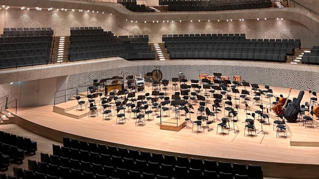 Interior da espaçosa sala de concertos Elbphilharmonie em Hamburgo, com cadeiras e instrumentos selecionados no palco Interior da espaçosa sala de concertos Elbphilharmonie em Hamburgo, com cadeiras e instrumentos selecionados no palco